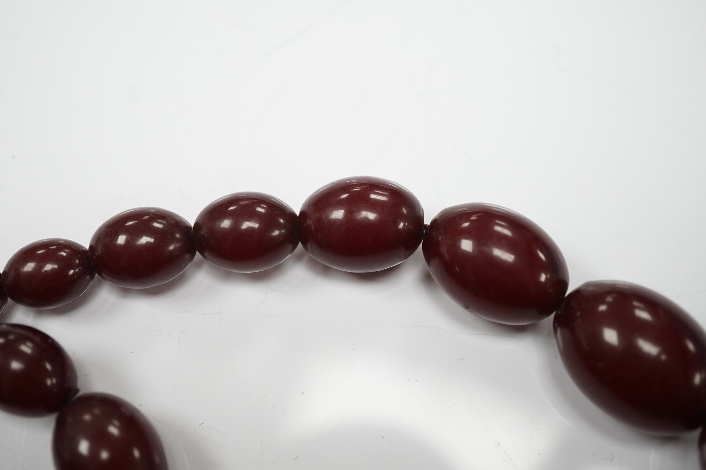 A single strand graduated simulated oval cherry amber bead necklace, 58cm, gross weight 80 grams.